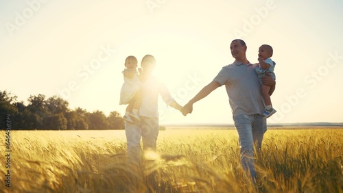 happy family in park wheat field. friendly family walks in a wheat field with two children baby toddlers in summer. happy family kid dream concept. big sunlight family silhouette in wheat field