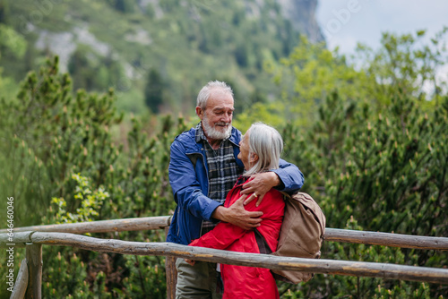 Senior tourists embracing on a wooden bridge during a hike in the autumn mountains.