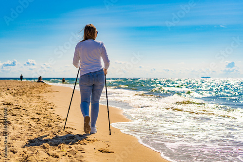 Nordic walking - woman exercising on beach
