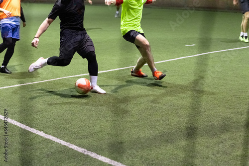 Futsal soccer football players with ball on artificial grass indoors. Space fort copy.