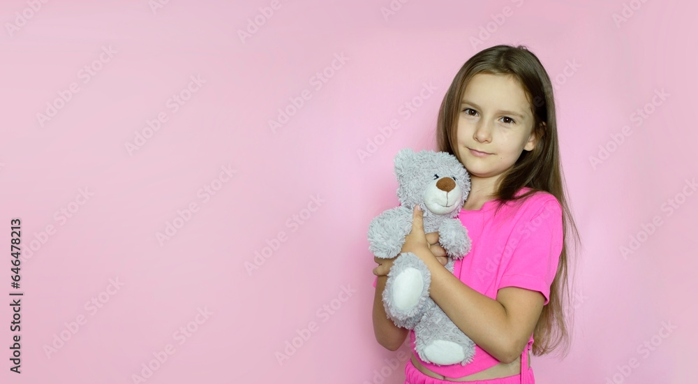 Happy child hugging and smiling teddy bear on pink background. Childhood, toys and shopping concept