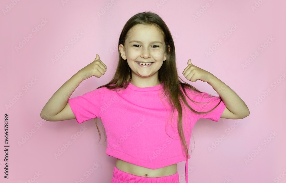 Charming schoolgirl in pink suit raises her fingers up in gesture on a pink background Charming schoolgirl in pink suit raises her fingers up in gesture on a pink background