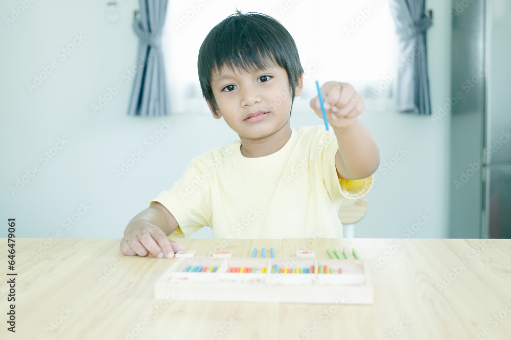 Asian kindergarten kid learn counting and holding mathematic wooden stick. Asian kindergarten kid learn counting and holding mathematic wooden stick.