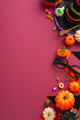 Embrace the carnival spirit with this kid's Halloween costume. Vertical top view shot of mystical hat, candy corn, eyewear and eerie decorations on crimson background. Ideal for bewitching experience