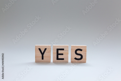Isolated three wooden letter blocks spelling YES, simple direct answer or agreement concept
