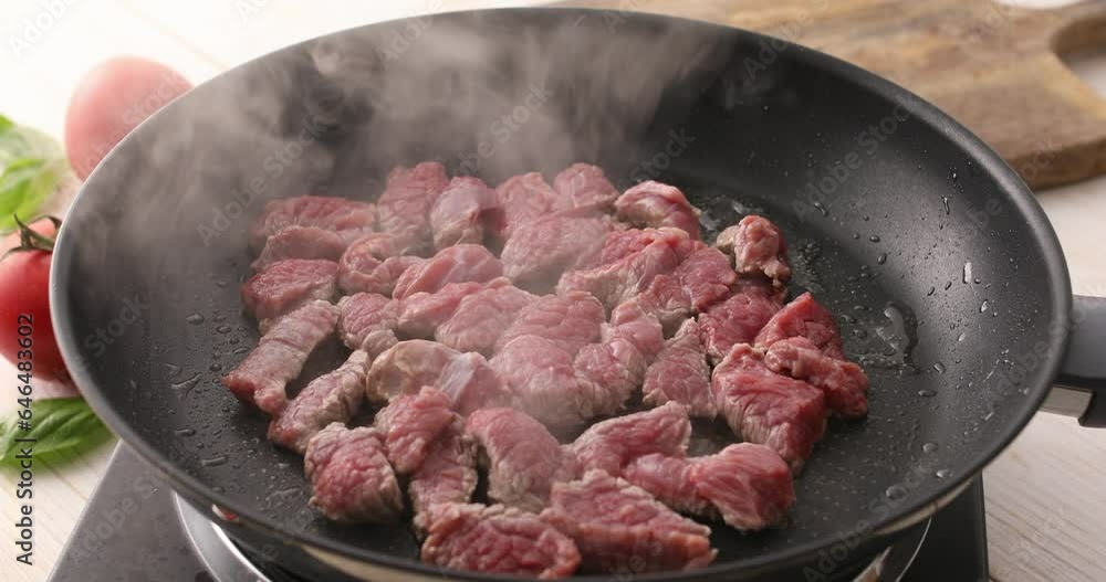 Sliced pieces of raw meat are fried in a frying pan. Roasting beef in a pan. Cooking in the kitchen. Food preparation. Sliced pieces of raw meat are fried in a frying pan. Roasting beef in a pan. Cooking in the kitchen. Food preparation.