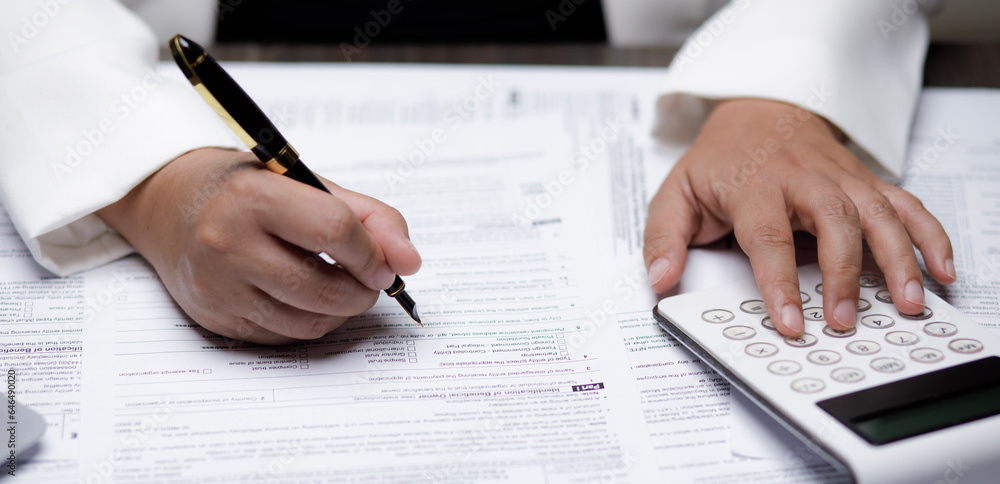 US IRS 1040 form or US Individual income tax Concept,accountant holding pen working on calculator business with data accounting documents and a laptop, pay tax in 2023 years,new year 2024 tax concept US IRS 1040 form or US Individual income tax Concept,accountant holding pen working on calculator business with data accounting documents and a laptop, pay tax in 2023 years,new year 2024 tax concept