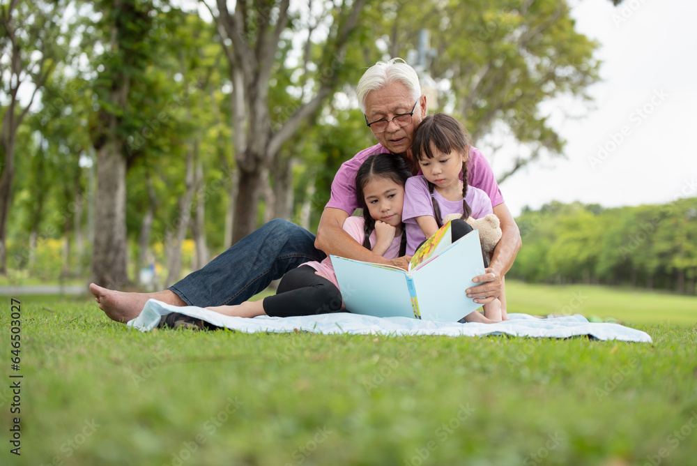 Happy Asian family children reading a book with her grandfather Happy Asian family children reading a book with her grandfather