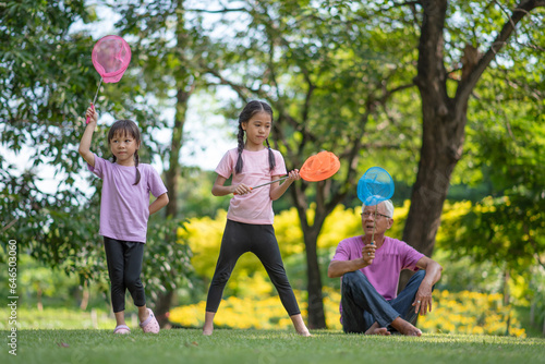 Εκτύπωση καμβά Happy Asian family children having fun and catches a net of insects with her gra