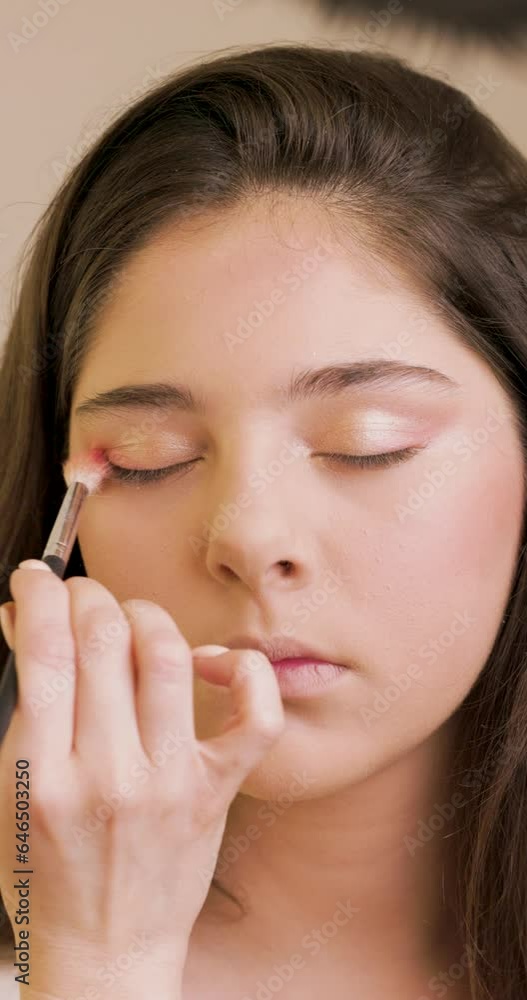 Portrait of a girl model at make-up artist who is applies eye shadow with a make-up brush to a her. Portrait of a girl model at make-up artist who is applies eye shadow with a make-up brush to a her.