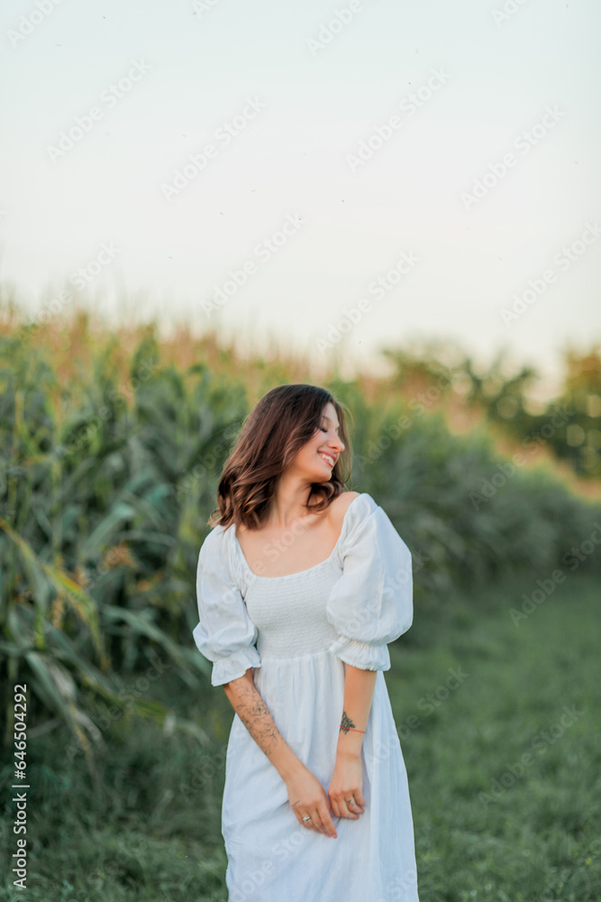 Young beautiful woman 26 years old in white simple dress in summer field. Green corn. Summer. Rustic style. Young beautiful woman 26 years old in white simple dress in summer field. Green corn. Summer. Rustic style.