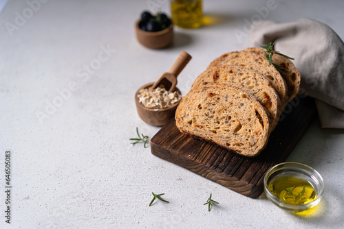 Homemade sourdough ciabatta slice bread with olives and rosemary on a white abstract table. Artisan bread