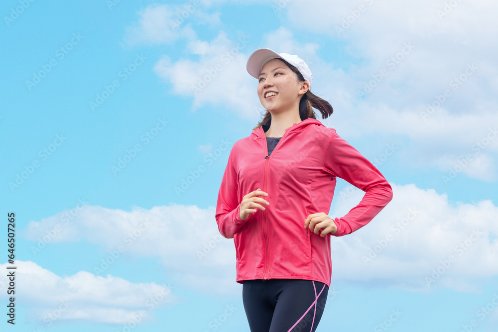 青空の下でジョギングをする若い女性 青空の下でジョギングをする若い女性