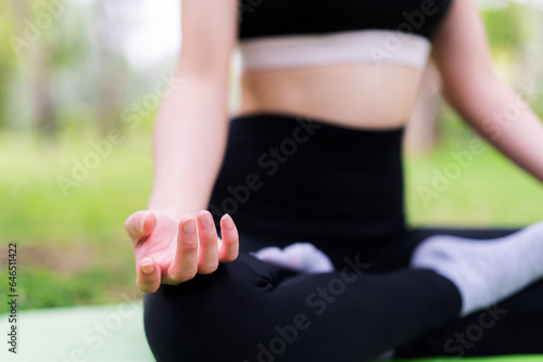 Young woman Finding Inner Peace in Yoga Pose at the Park. Yoga and Meditation Concept. Female exercising and stretching in Nature.