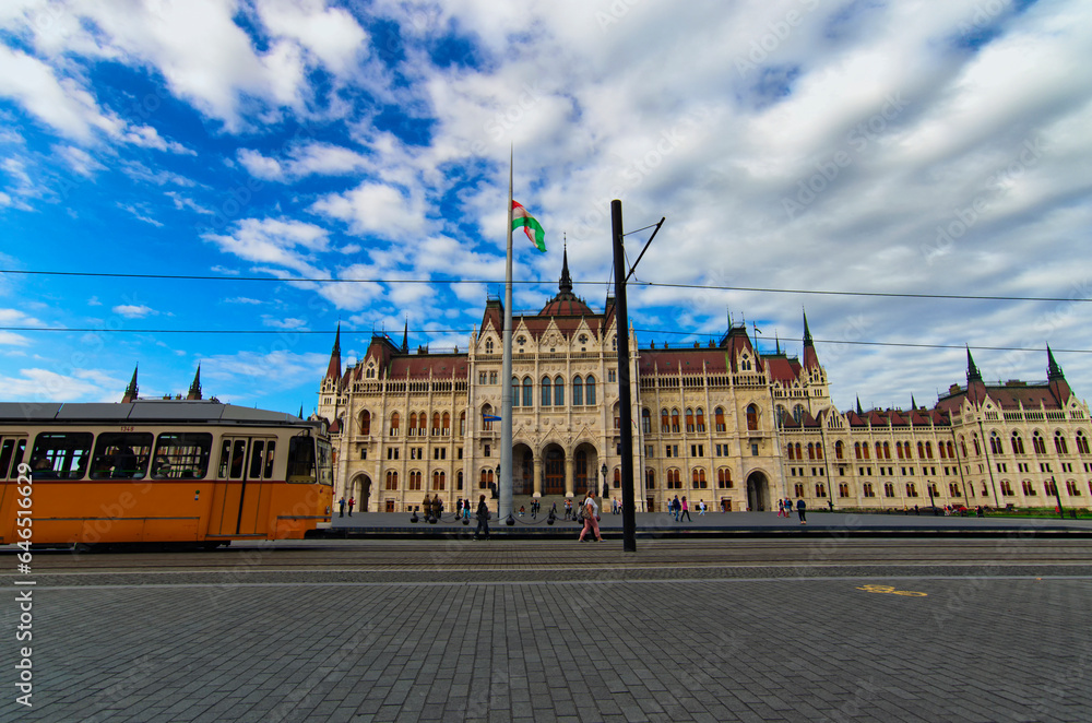 Wide-angle landscape view of vintage yellow tram against Hungarian Parliament in Budapest city, Hungary. Famous touristic place and romantic travel destination