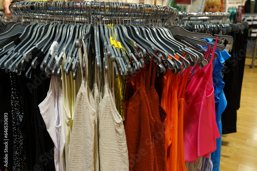 Women's tank tops hang on hangers in a clothing store.