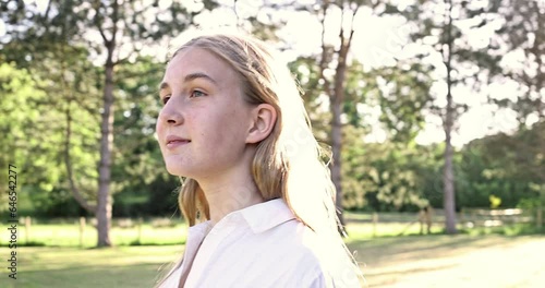 Happy girl in rays of the sun. Girl face in park close-up. Dream girl. Happy face of a child in rays of sun. Child smiles at camera. Girl dream.