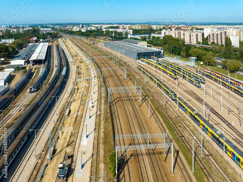 Krakow, Poland. Big train hub, outdoor and indoor garage with train sheds, fast city trains, old and new carriages, many railroad tracks, rails and electric traction. Aerial view photo