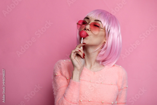 girl with pink short hair licks and sucks chupachups with pleasure, sexy concept photo