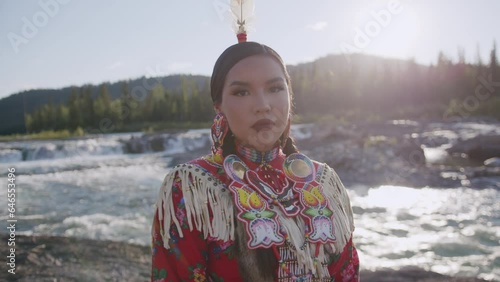 Beautiful Portrait Shot of Young Indigenous Woman wearing traditional North American Native Regalia Tsu'Tina Nation Alberta Canada Down by the river at sunset.