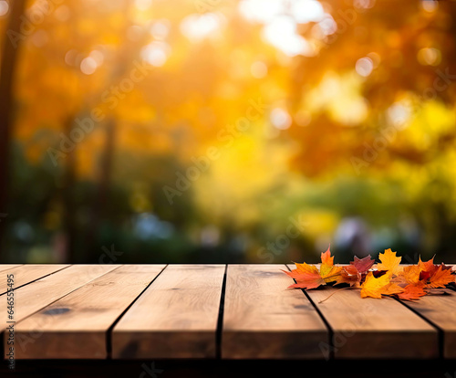 Autumn or Thanksgiving background with rustic wooden planks  leaves and yellow  orange fall colors on the blurred-out trees on the background. Texture with copy space.