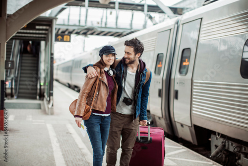 Young couple traveling and walking in a train station with their suitcases