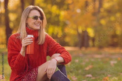 girl in a red sweater with a thermal mug in autumn in the park  autumn season concept