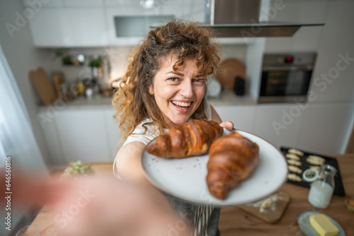 Tela One adult caucasian woman stand in the kitchen with fresh croissant