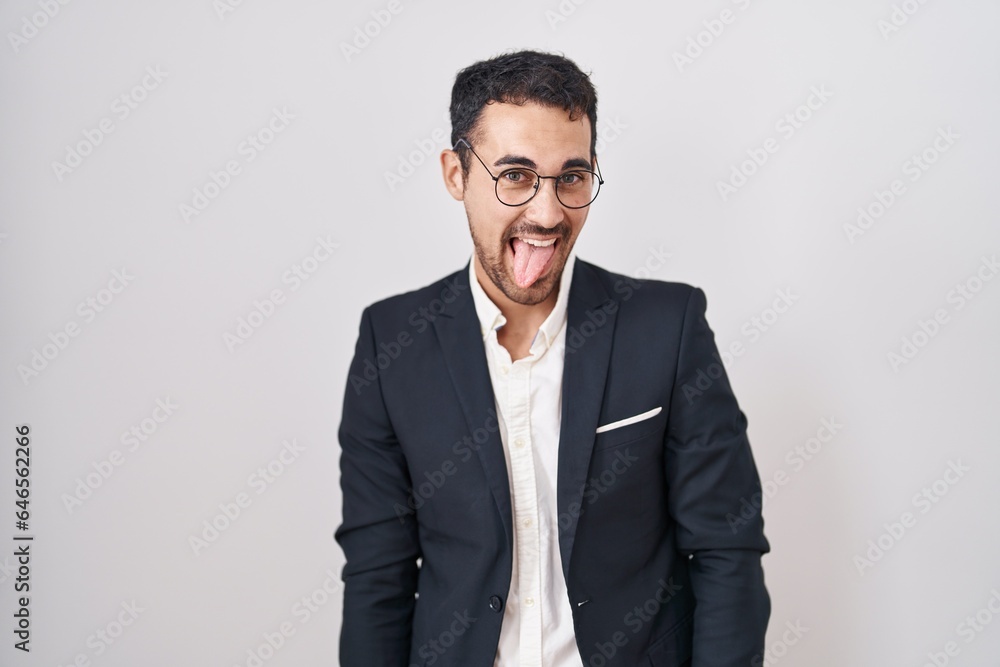 Handsome business hispanic man standing over white background sticking tongue out happy with funny expression. emotion concept. Handsome business hispanic man standing over white background sticking tongue out happy with funny expression. emotion concept.