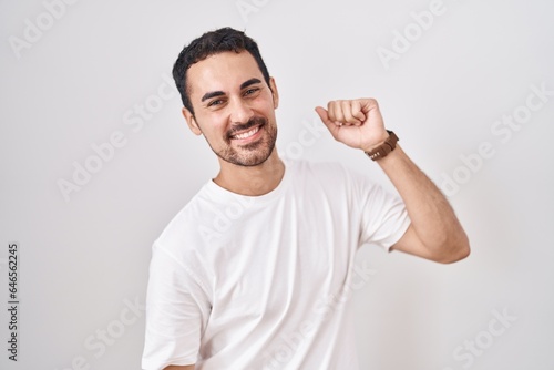 Handsome hispanic man standing over white background dancing happy and cheerful, smiling moving casual and confident listening to music