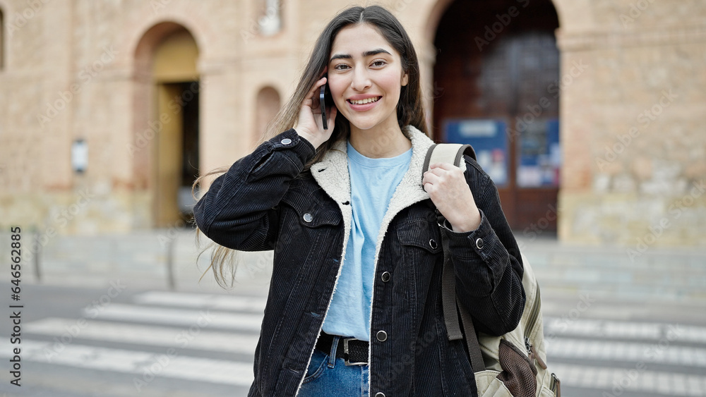 Young beautiful hispanic woman student smiling confident talking on smartphone at street