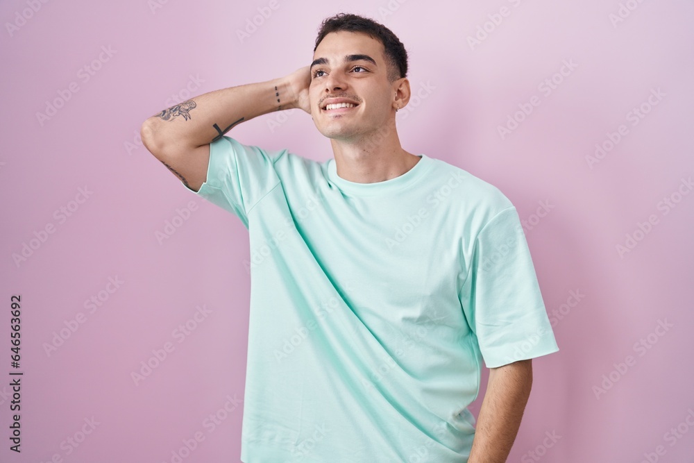 Handsome hispanic man standing over pink background smiling confident touching hair with hand up gesture, posing attractive and fashionable Handsome hispanic man standing over pink background smiling confident touching hair with hand up gesture, posing attractive and fashionable