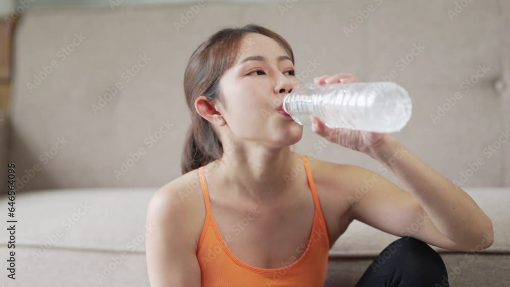 Asian woman in sportswear drinking water after workout exercise at home. Asian woman in sportswear drinking water after workout exercise at home.