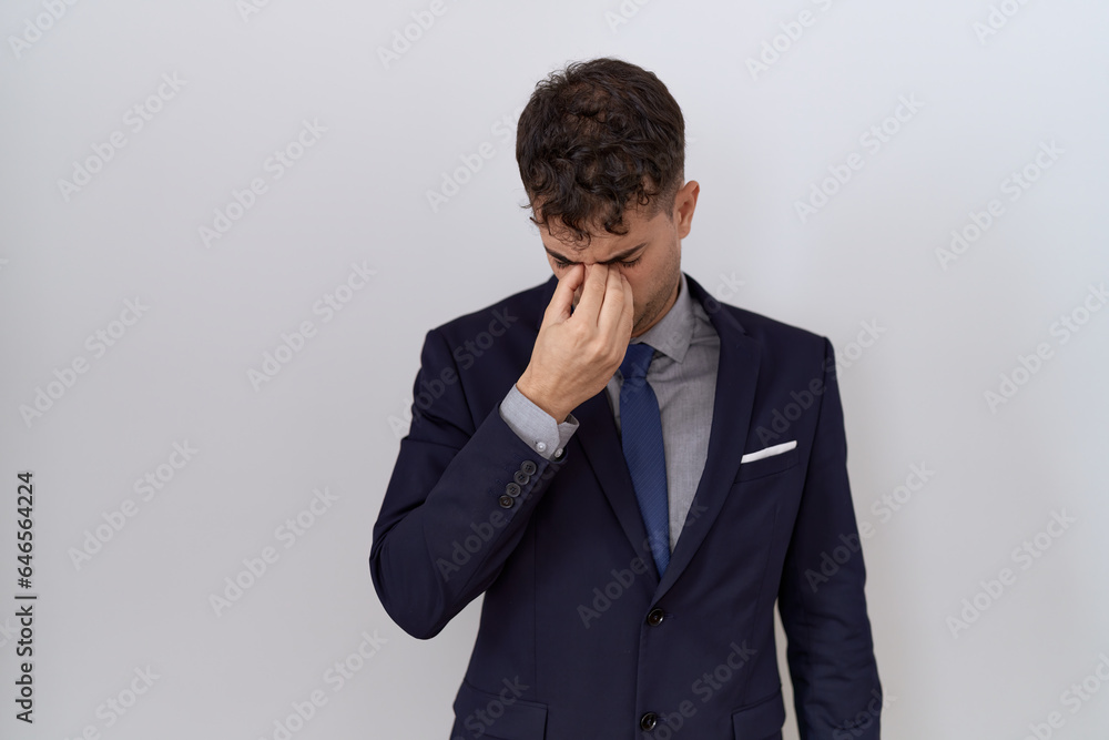 Young hispanic business man wearing suit and tie tired rubbing nose and eyes feeling fatigue and headache. stress and frustration concept. Young hispanic business man wearing suit and tie tired rubbing nose and eyes feeling fatigue and headache. stress and frustration concept.