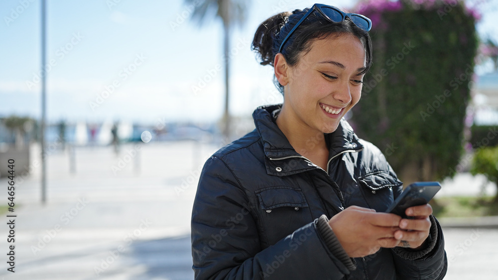 Young beautiful hispanic woman using smartphone smiling at street Young beautiful hispanic woman using smartphone smiling at street