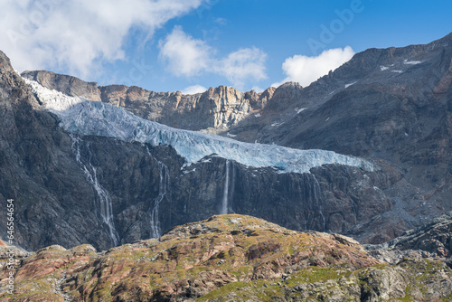 View of Fellaria Glacier from Bignami hut, thick ice with crevasses, waterfall from the glacier to the rocky peak below in front of the lake. global warming and climate change melting the ice 