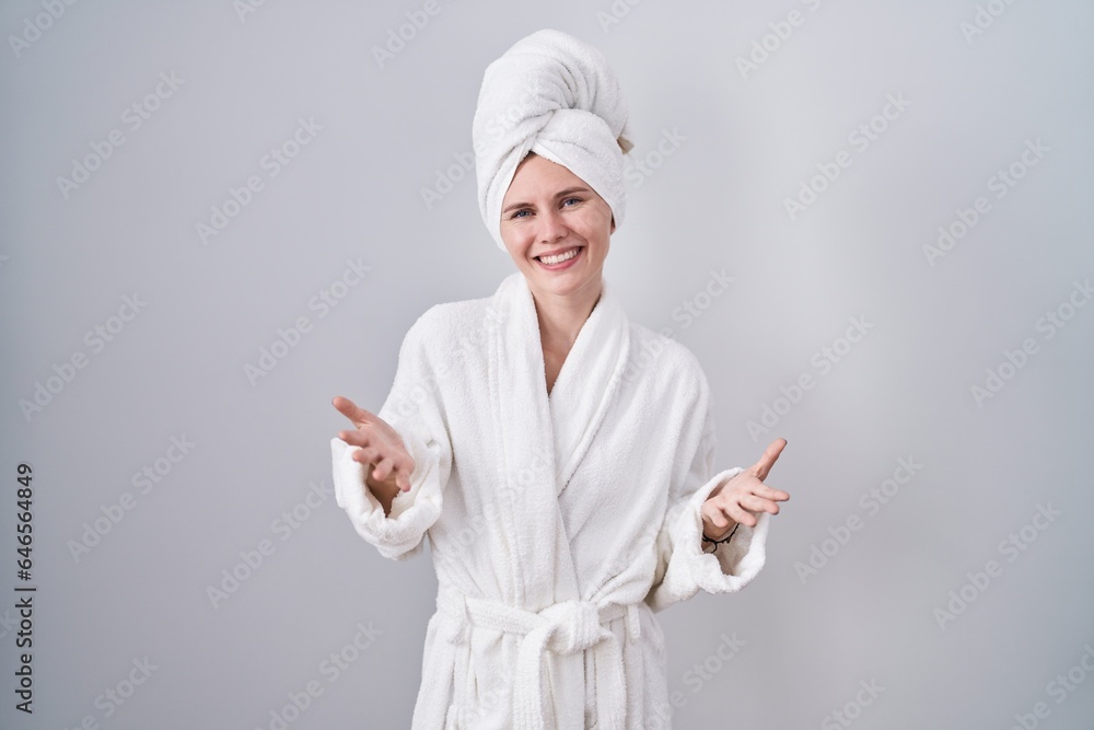 Blonde caucasian woman wearing bathrobe smiling cheerful with open arms as friendly welcome, positive and confident greetings Blonde caucasian woman wearing bathrobe smiling cheerful with open arms as friendly welcome, positive and confident greetings