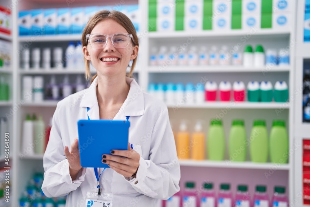 Young blonde woman pharmacist smiling confident using touchpad at pharmacy