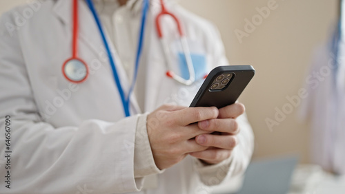 Young hispanic man doctor using smartphone at clinic