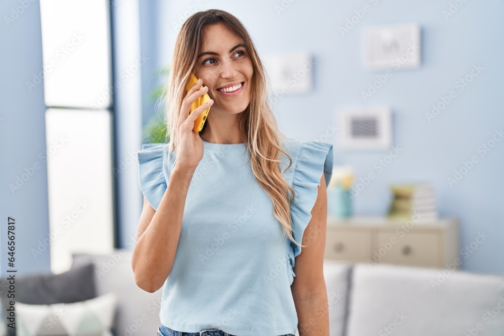Young woman talking on smartphone standing at home Young woman talking on smartphone standing at home