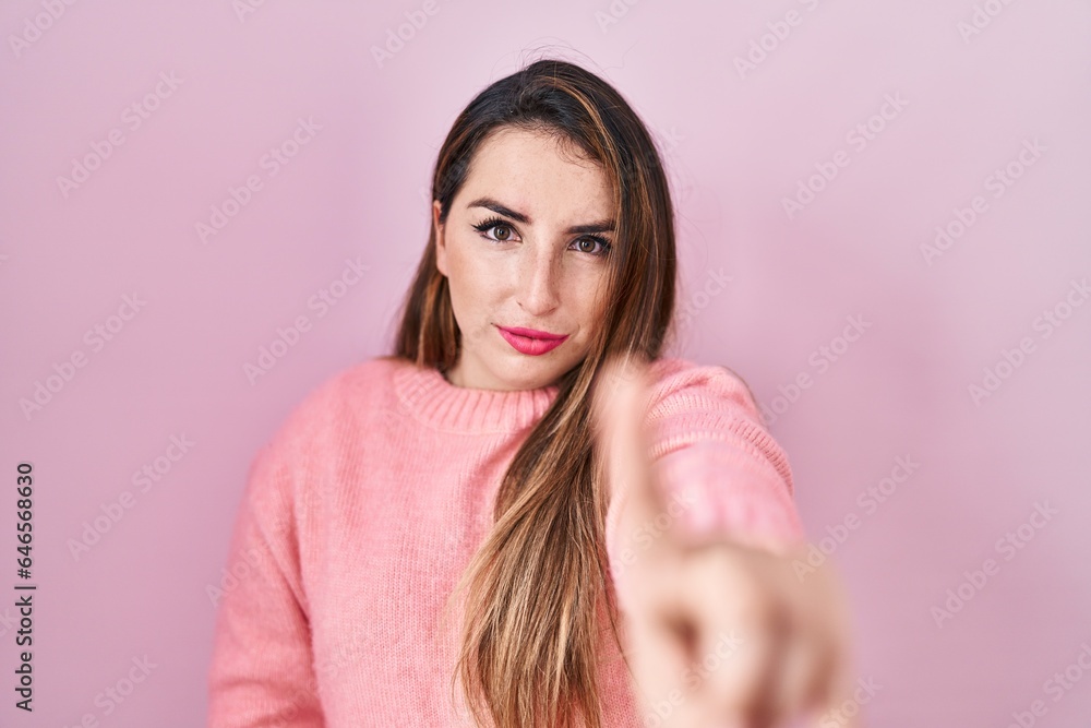 Young hispanic woman standing over pink background pointing with finger up and angry expression, showing no gesture Young hispanic woman standing over pink background pointing with finger up and angry expression, showing no gesture