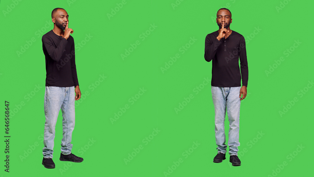 Young adult showing hush sign on camera, expressing privacy and silence in studio. Private person doing mute symbol and being confidential, keeping secret over full body green screen. Young adult showing hush sign on camera, expressing privacy and silence in studio. Private person doing mute symbol and being confidential, keeping secret over full body green screen.