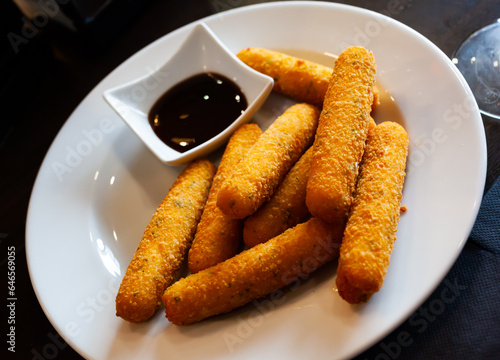 Appetizing snack of fried mozzarella fingers served with berry sauce..