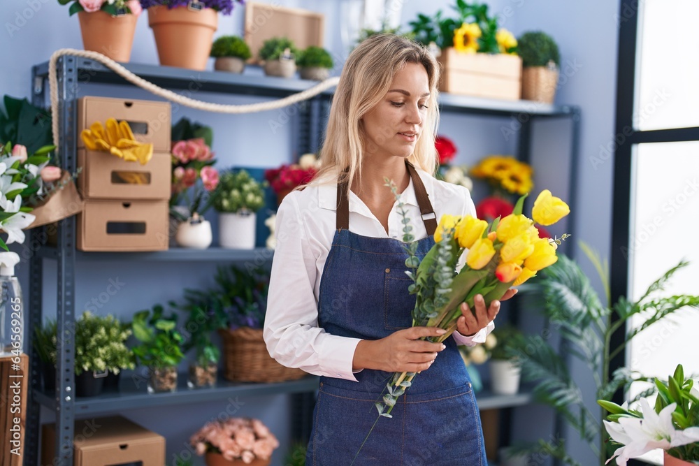 Young blonde woman florist holding bouquet of flowers at florist