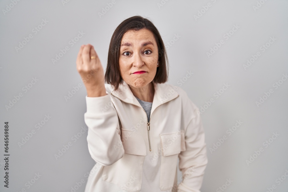 Middle age hispanic woman standing over isolated background doing italian gesture with hand and fingers confident expression Middle age hispanic woman standing over isolated background doing italian gesture with hand and fingers confident expression