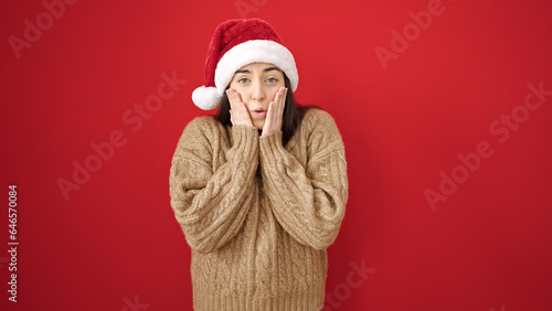 Young beautiful hispanic woman smiling confident wearing christmas hat over isolated red background