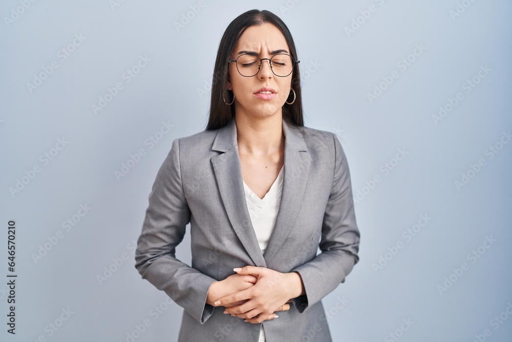 Hispanic business woman wearing glasses with hand on stomach because indigestion, painful illness feeling unwell. ache concept. Hispanic business woman wearing glasses with hand on stomach because indigestion, painful illness feeling unwell. ache concept.