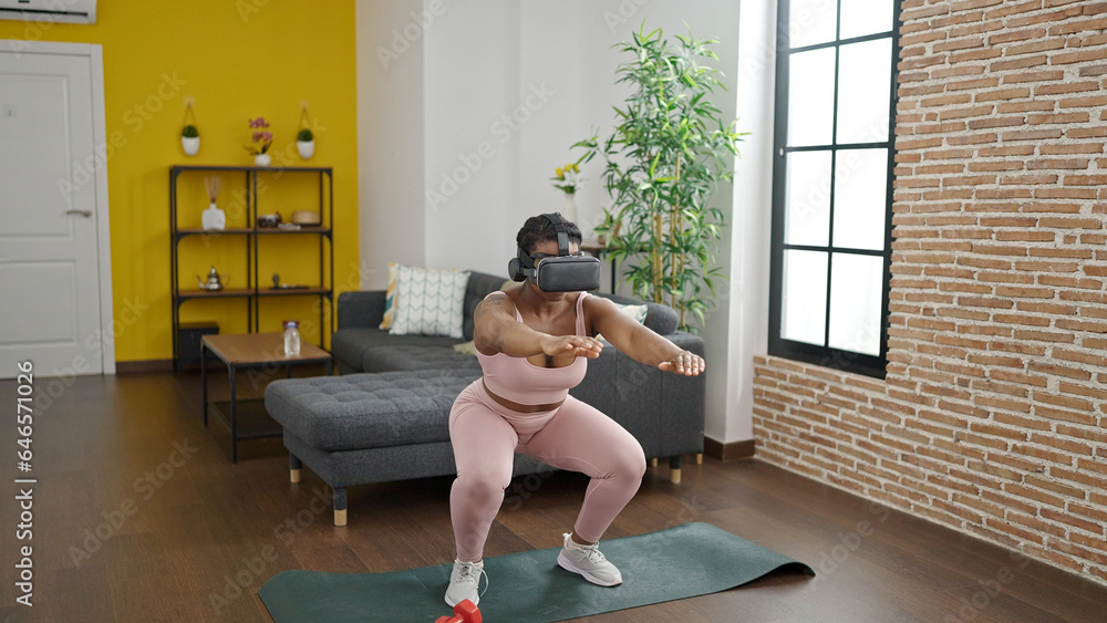Obraz premium African american woman training legs exercise using virtual reality glasses at home