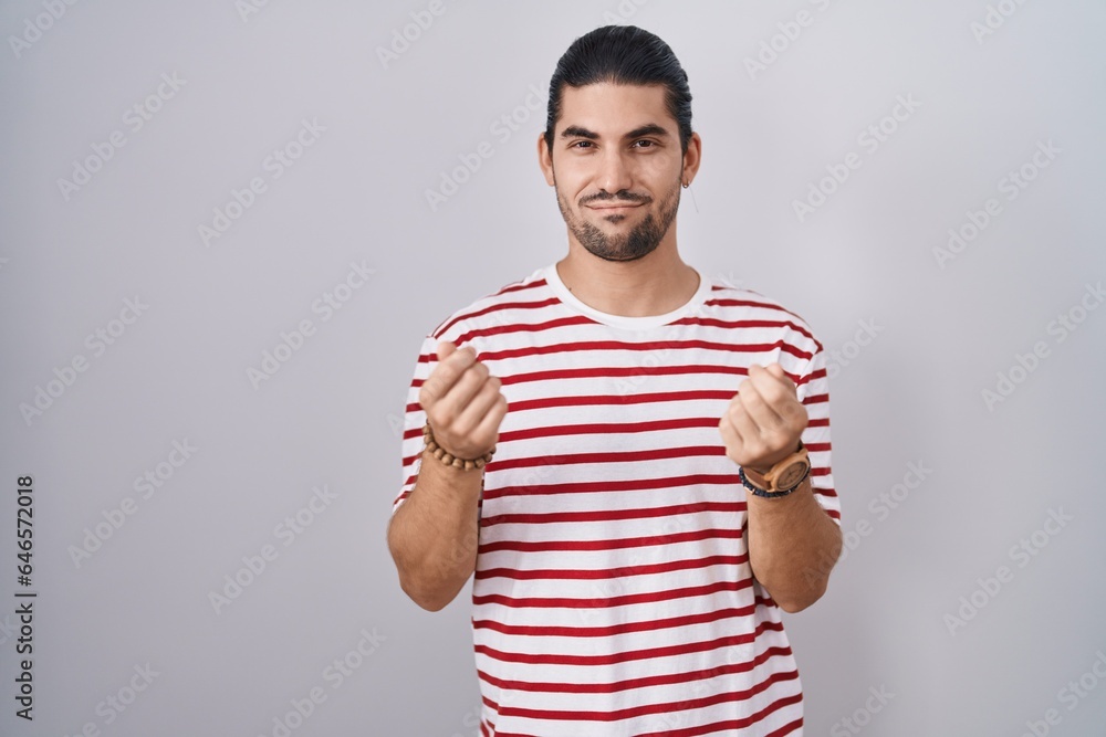 Hispanic man with long hair standing over isolated background doing money gesture with hands, asking for salary payment, millionaire business Hispanic man with long hair standing over isolated background doing money gesture with hands, asking for salary payment, millionaire business