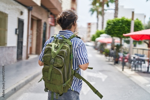 Young hispanic man tourist wearing backpack walking at street